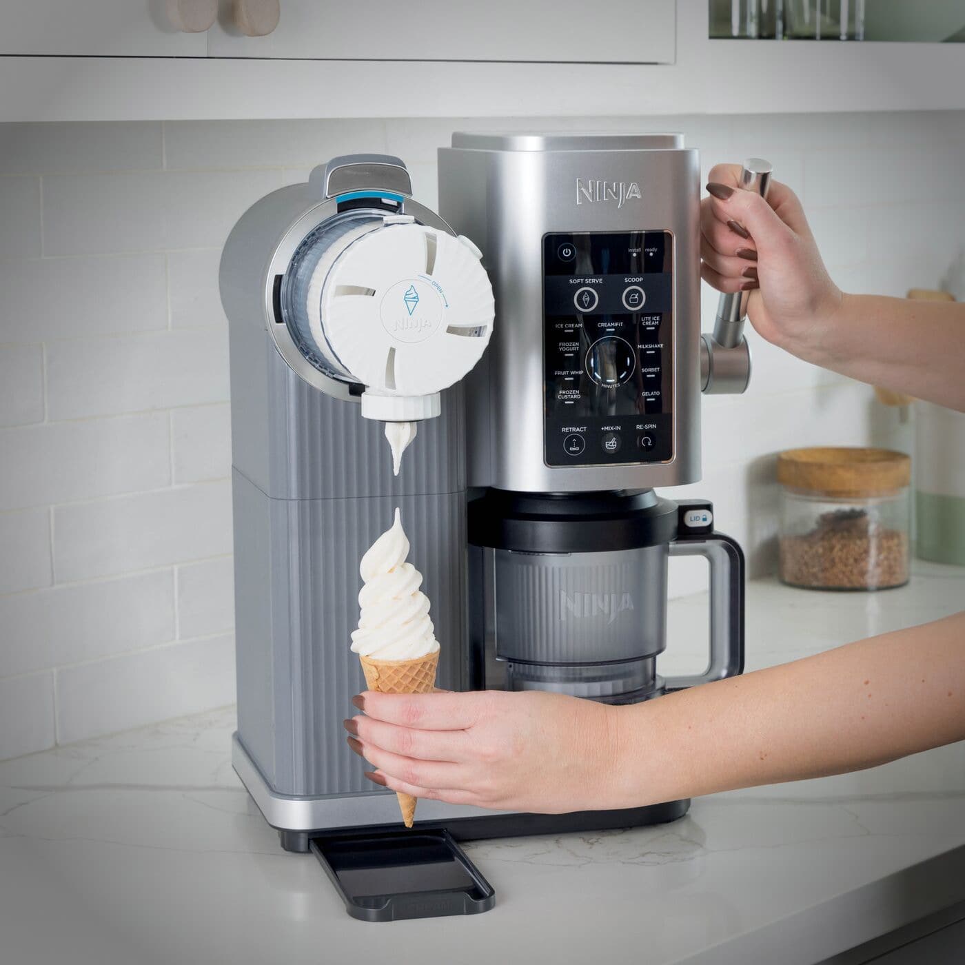 Ninja CREAMi in use as a person dispenses soft serve into a cone using the motorized swirl function.